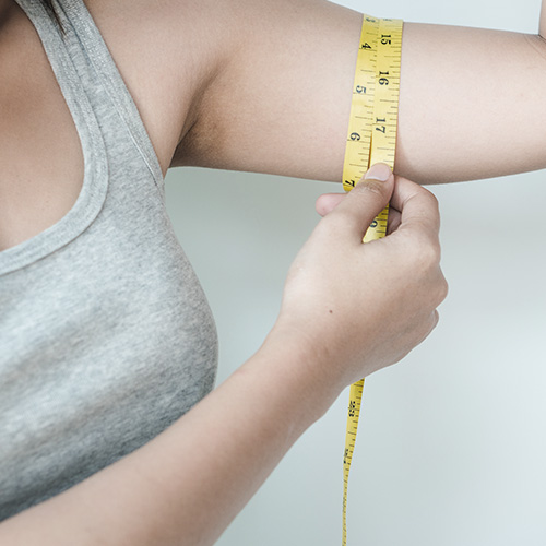 Selectively target specific areas for body shaping - Woman measuring her arm