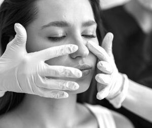 Close-up of a woman's face receiving a collagen remodeling treatment from a professional in white gloves, aimed at generating heat to stimulate collagen contraction and tighten the dermis layer.