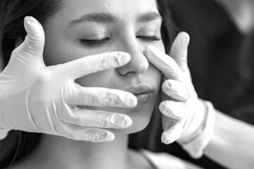 Close-up of a woman's face receiving a collagen remodeling treatment from a professional in white gloves, aimed at generating heat to stimulate collagen contraction and tighten the dermis layer.