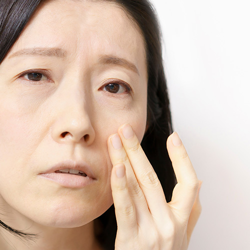 Woman examining her face for signs of reduced skin elasticity.