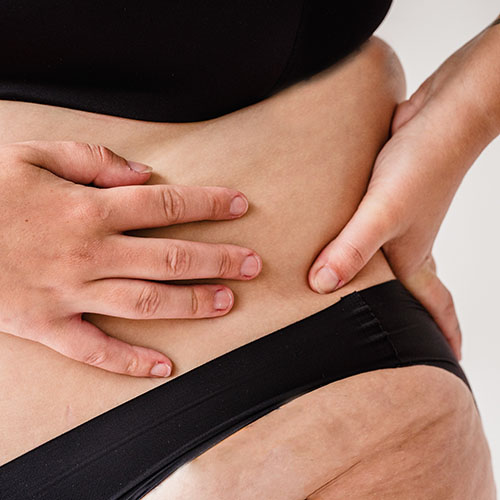 Person pinching excess fat on the belly, focusing on body fat reduction