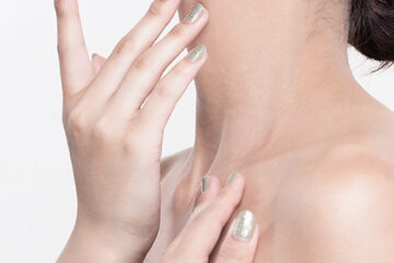 Close-up of a person gently touching their neck to illustrate focus on improving neck wrinkles.