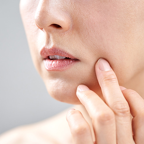 Close-up of a woman touching her face, addressing concerns about sagging skin