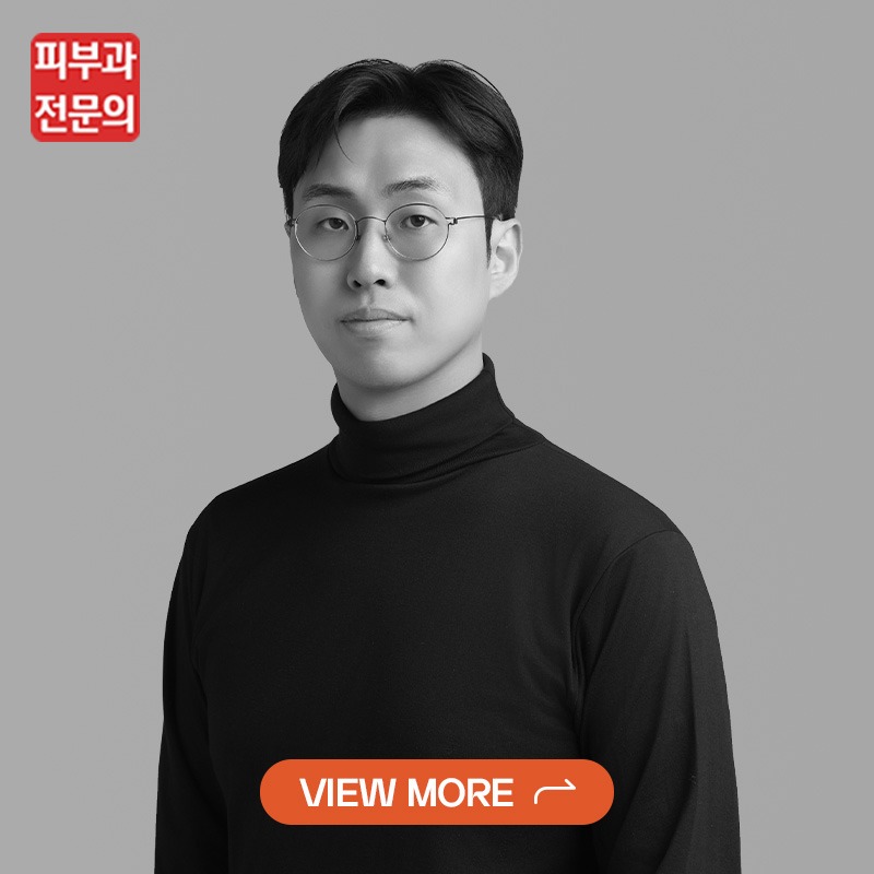 Portrait of a person in a black turtleneck and glasses, grayscale, with a red brand logo top-left and an orange 'VIEW MORE' CTA button overlay.