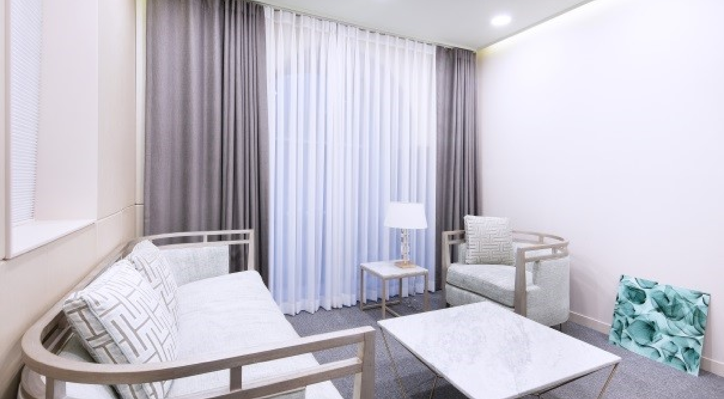 Modern and elegant living room with grey curtains, white sheer drapes, minimalist sofa and armchair, marble coffee table, and stylish decor